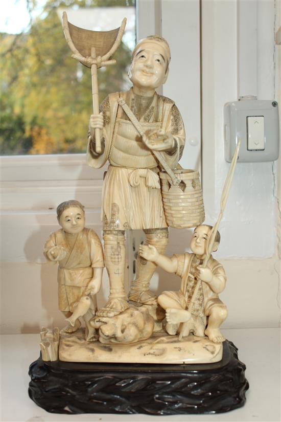 A large Japanese sectional walrus ivory okimono of a fisherman and two boys, early 20th century height including wood stand, 40cm